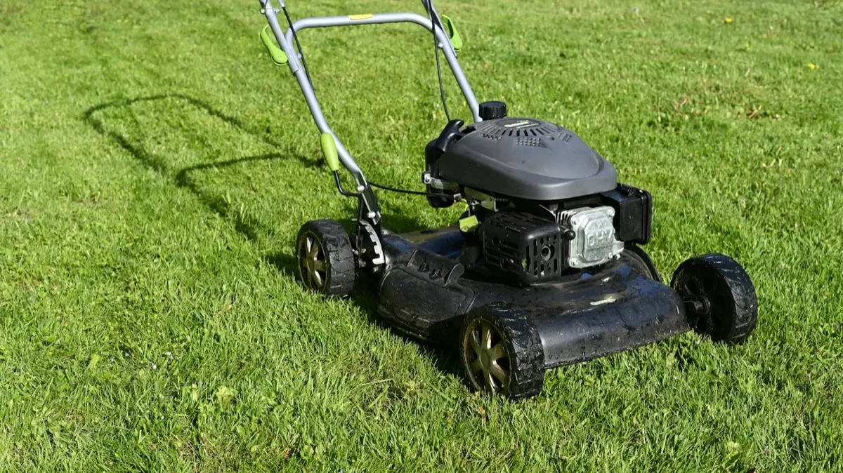 A walk-behind lawn mower standing on freshly cut green grass.