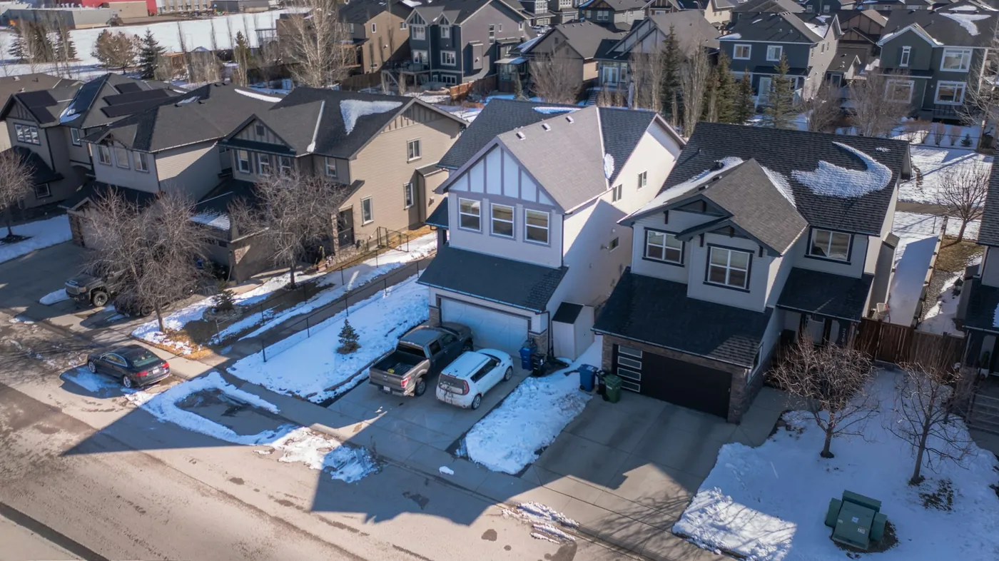 An aerial view of a suburban neighbourhood after snowfall, with driveways and the road cleared back to the pavement.